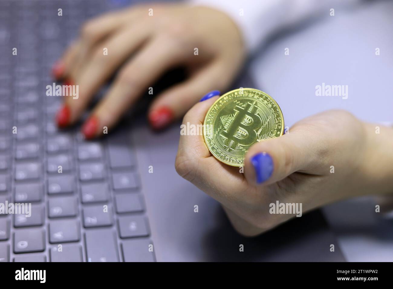 Bitcoin in den Händen eines Mädchens, das am Laptop arbeitet, elektronisches dezentralisiertes Geld, Kryptowährung Stockfoto