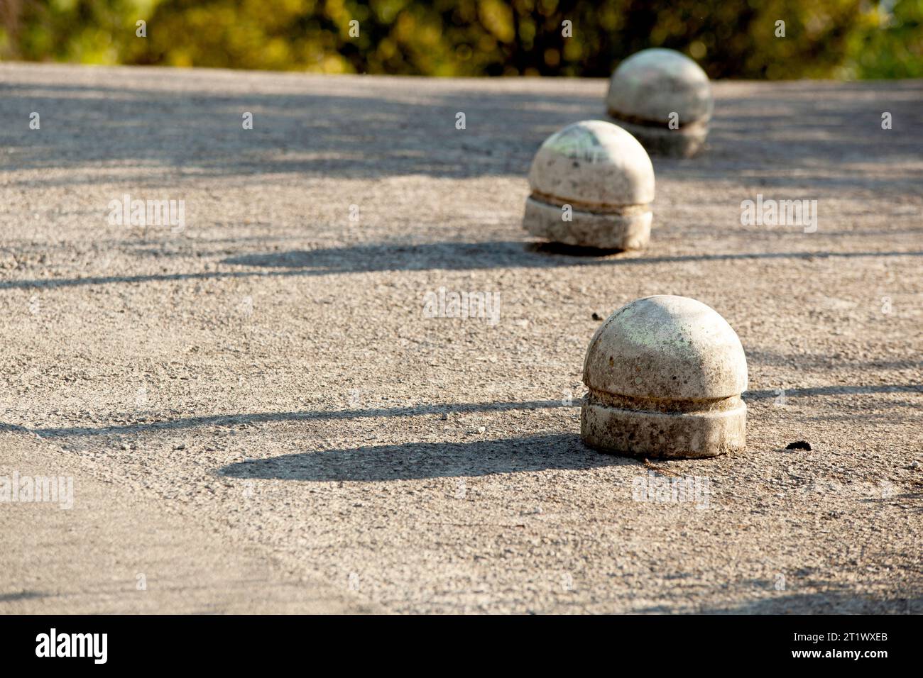 Graue Betonhalbkugeln behindern den Verkehr auf grauem Asphalt. Sonniger Tag, Schatten auf dem Asphalt. Montenegro. Budva. Horizontal. Hochwertige Fotos. Stockfoto