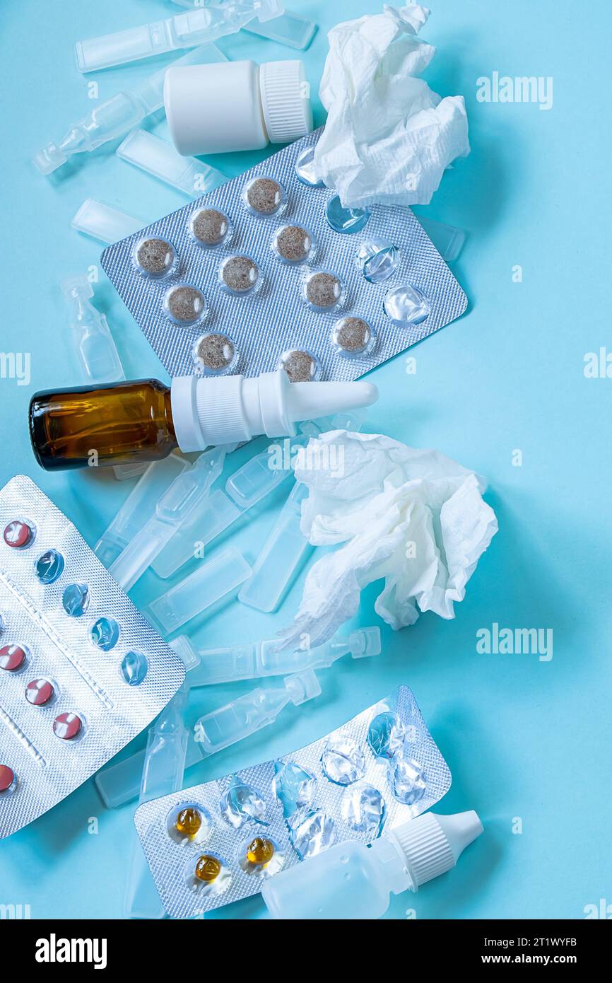 Erkältungszeit und Krankheitszeit. Medikamente und Pillen auf blauem Hintergrund. Nasenspray für laufende Nase und Gewebe. Stockfoto