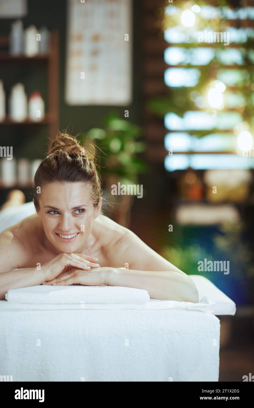 Gesundheitszeit. Glückliche moderne 40-jährige Frau im Massageschrank, die auf Massagetisch liegt. Stockfoto