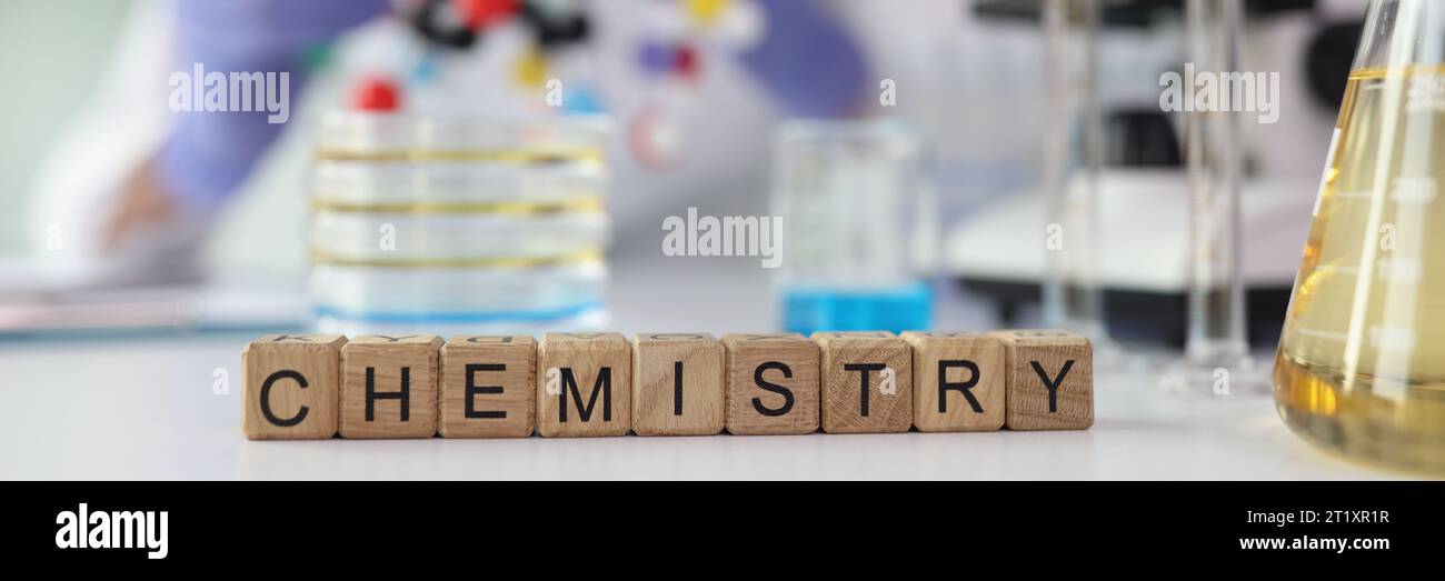 Word Chemistry aus Würfeln in der Nähe von Laborglasgeräten Stockfoto