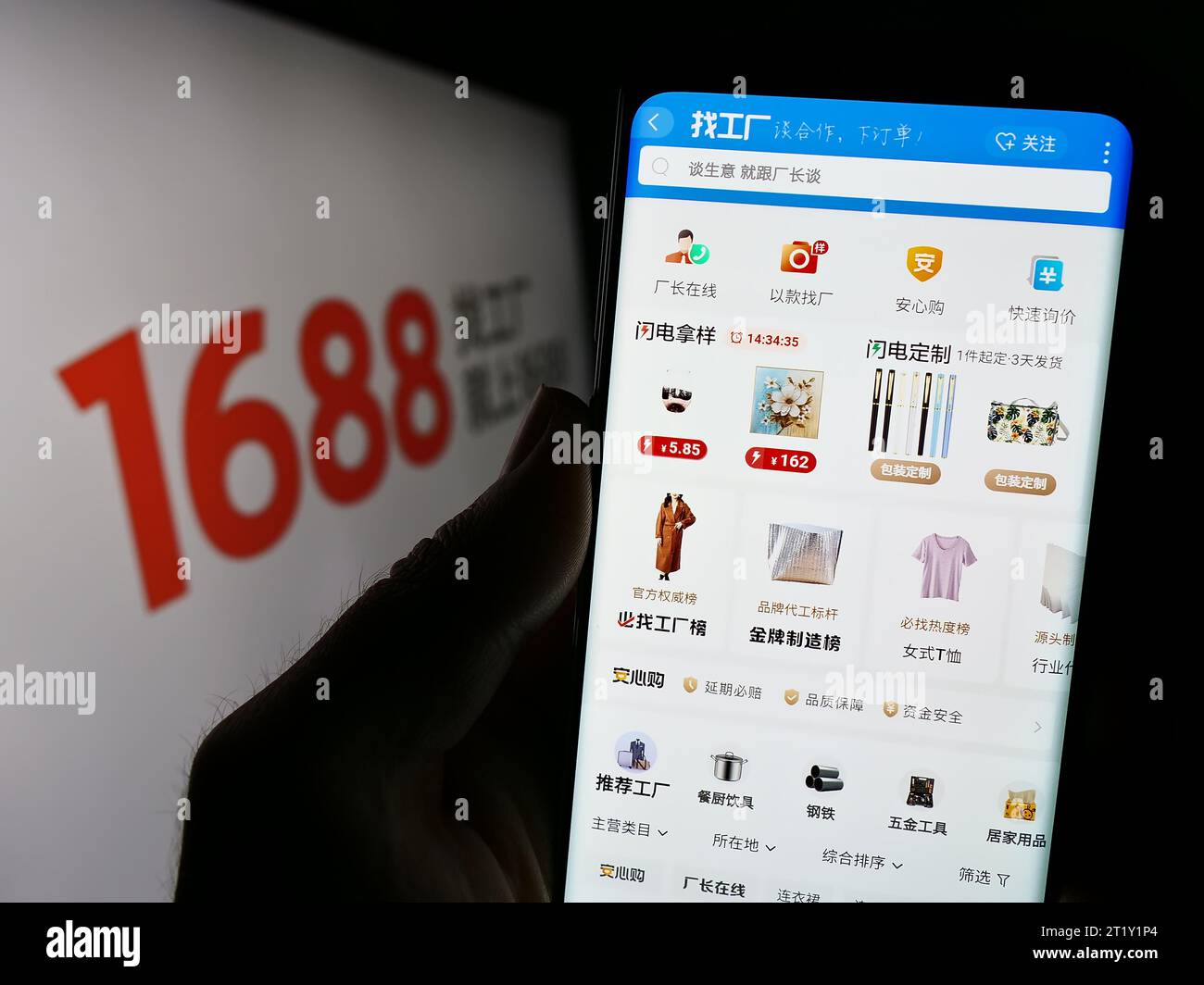 Person, die ein Mobiltelefon hält, mit der Webseite des chinesischen Online-Shops 1688.com (Alibaba) vor dem Geschäftslogo. Konzentrieren Sie sich auf die Mitte des Telefondisplays. Stockfoto