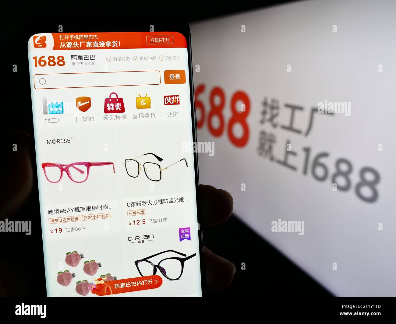 Person mit Smartphone und Webseite des chinesischen Online-Shops 1688.com (Alibaba) vor dem Firmenlogo. Konzentrieren Sie sich auf die Mitte des Telefondisplays. Stockfoto