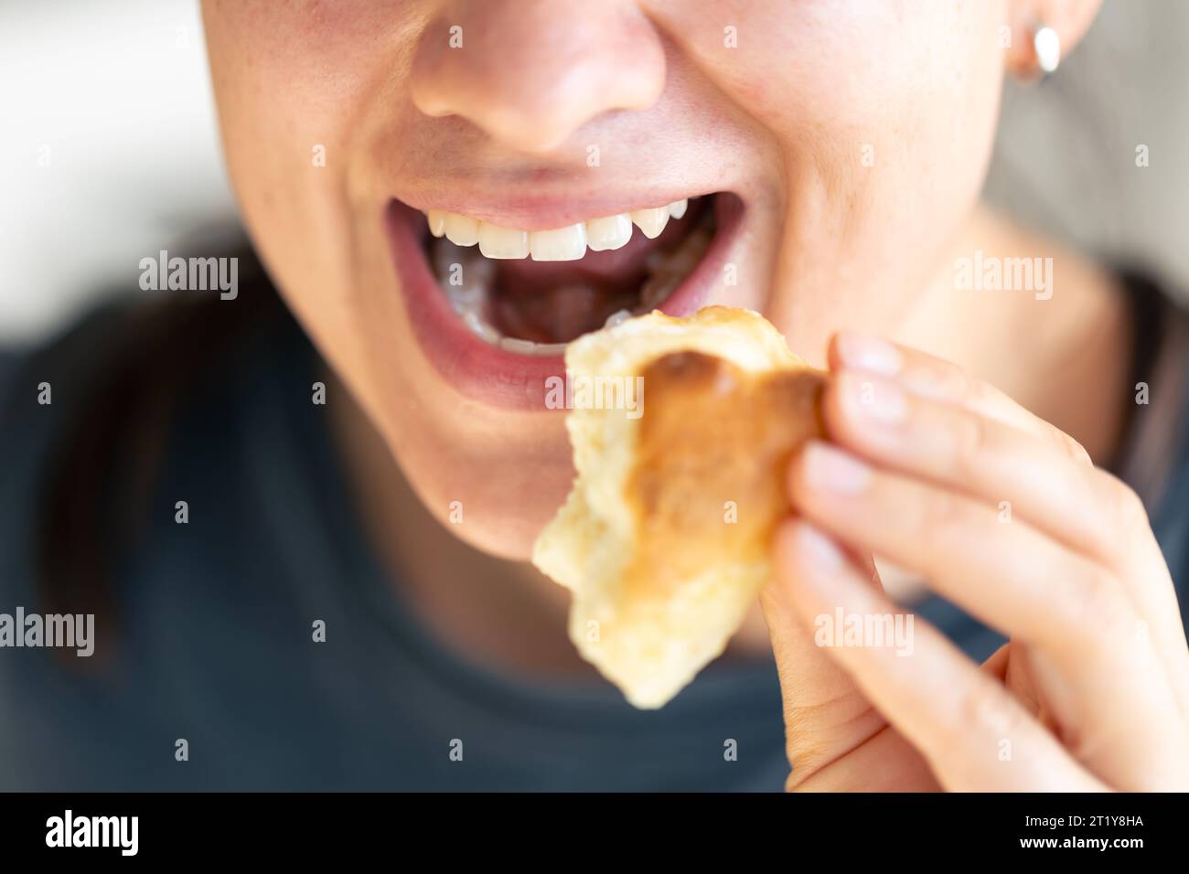 Detaillierte Aufnahme einer Frau, die frisches Brötchen isst. Stockfoto