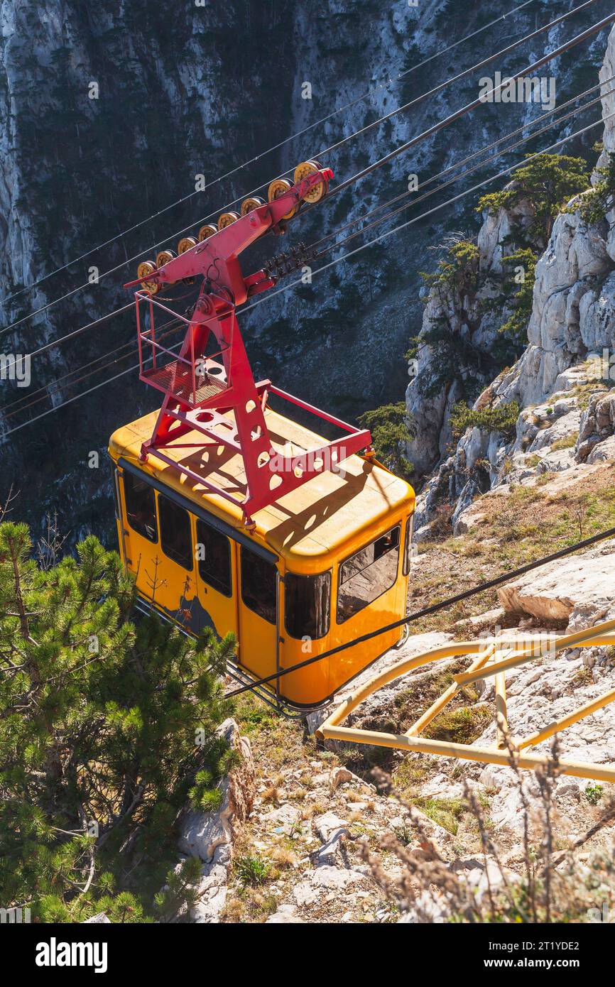 Gelbe Kabine einer Seilbahn führt an einem sonnigen Tag zum Ai-Petri Berg, vertikales Foto Stockfoto
