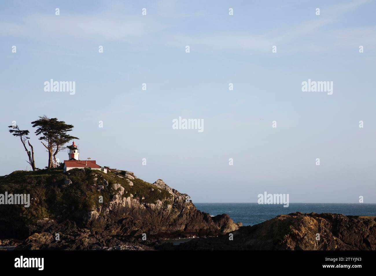 Ein Leuchtturm befindet sich auf einem Felsvorsprung mit Blick auf das tiefblaue Meer. Stockfoto