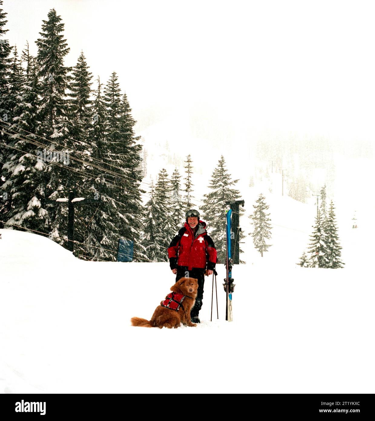 Court Wing, ein legendärer Skipatrouille am Steven's Pass, WA, mit seinem Hund an einem verschneiten Tag. Stockfoto