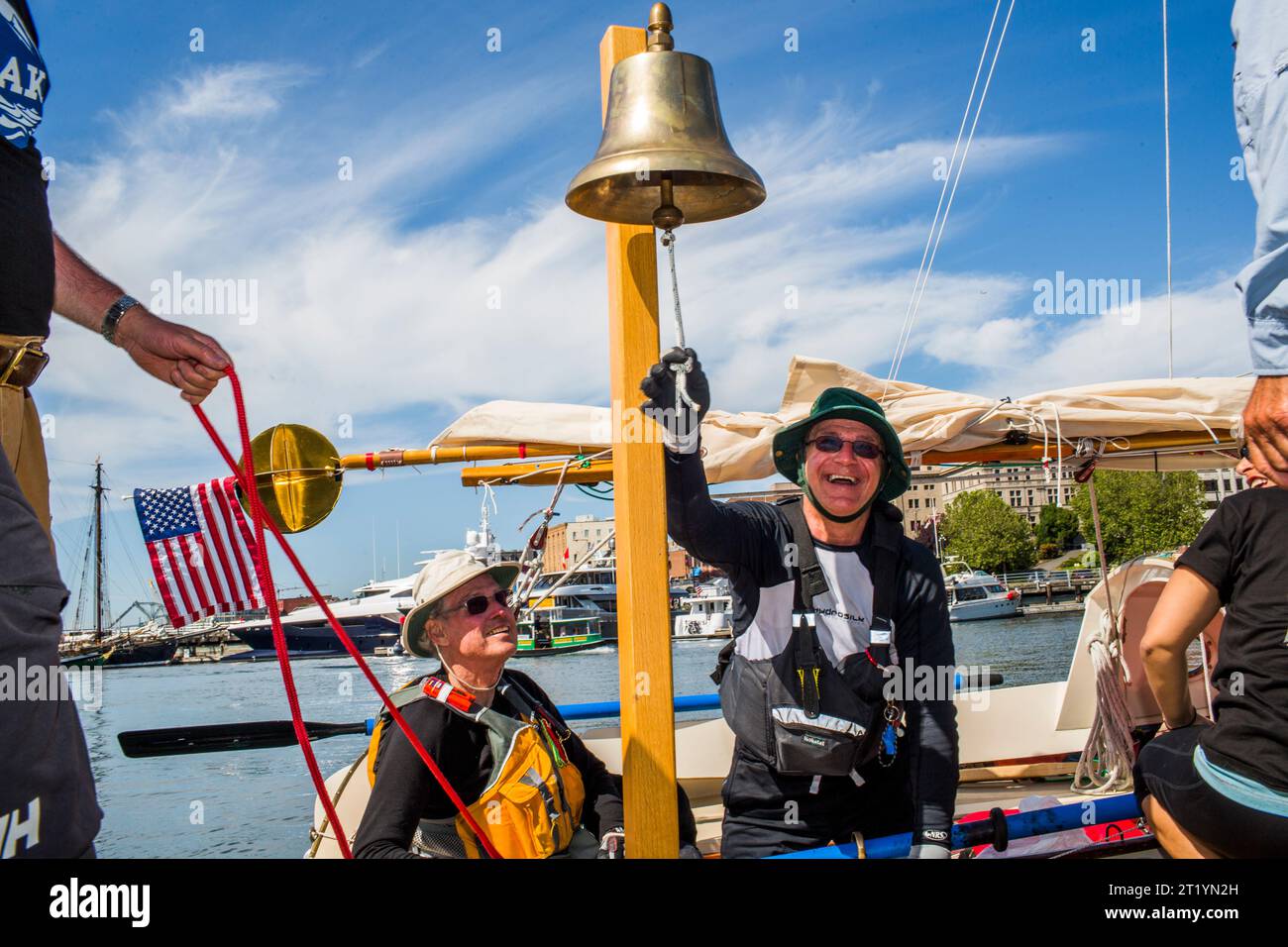 Ein Mann läutet die Glocke und weist darauf hin, dass er die erste Etappe des Race to Alaska beendete, einem 750 Meilen langen, nicht motorisierten Bootsrennen von Port Townsend, WA nach Ketchikan, Alaska. Stockfoto