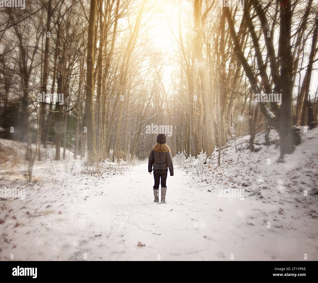 Ein junges Mädchen, das im Winter auf verschneiten Pfaden steht Stockfoto