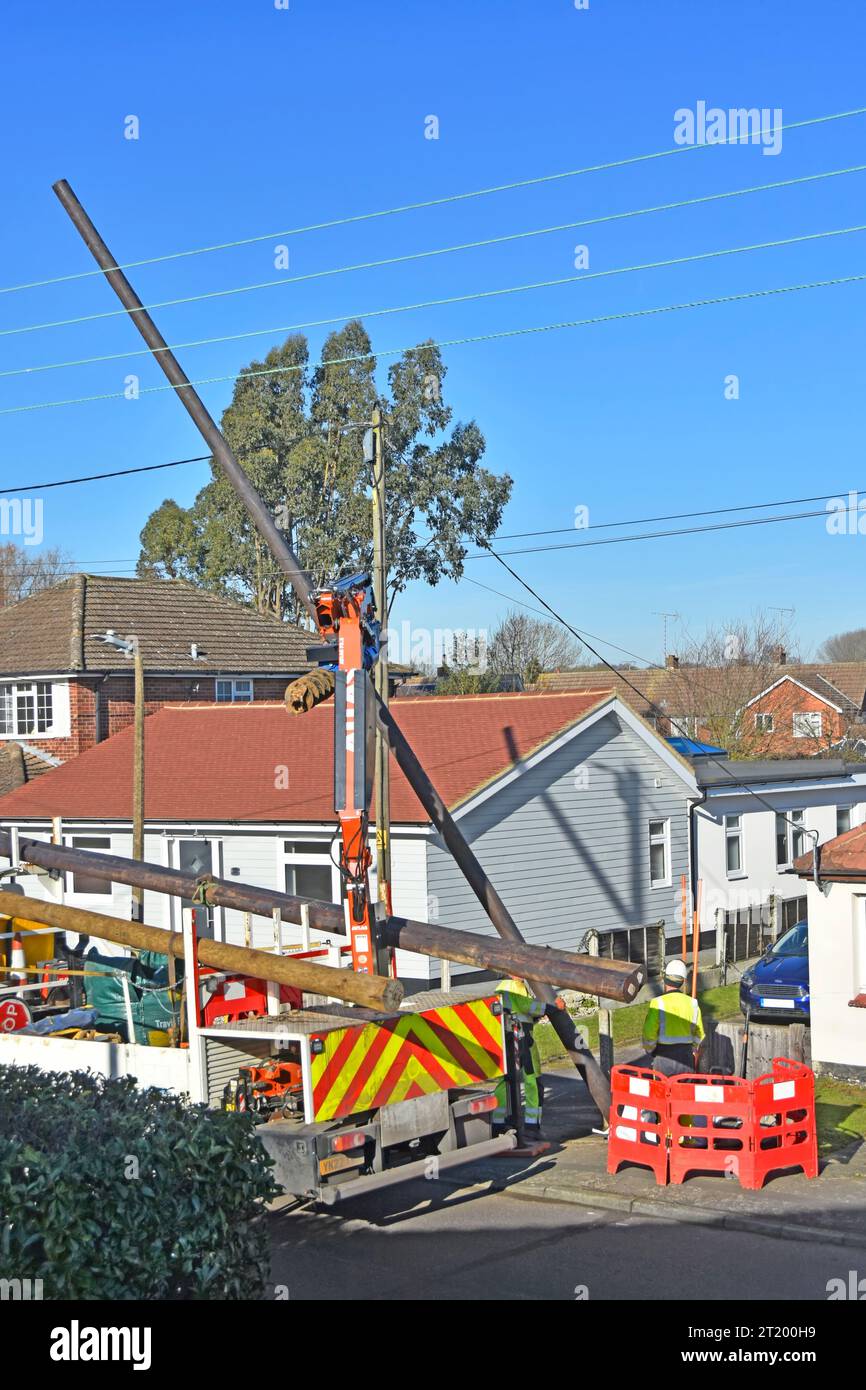 Elektroingenieure installieren einen neuen Holzständer, um Ersatz-Freileitungen zu Häusern in der Wohnstraße England UK zu transportieren Stockfoto