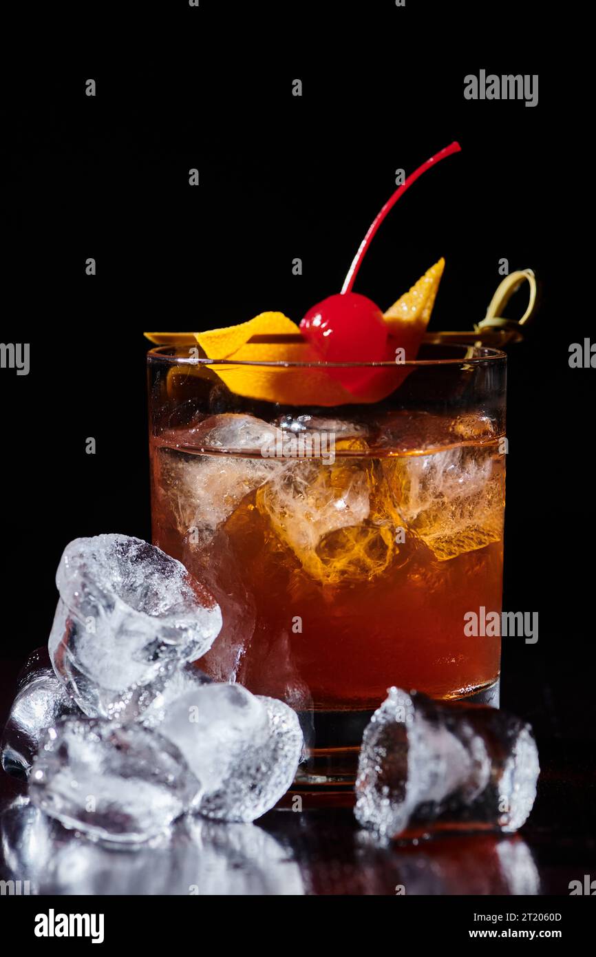 Eleganter negroni-Cocktail mit Kirsch und Eis vor schwarzem Hintergrund, Konzept Stockfoto
