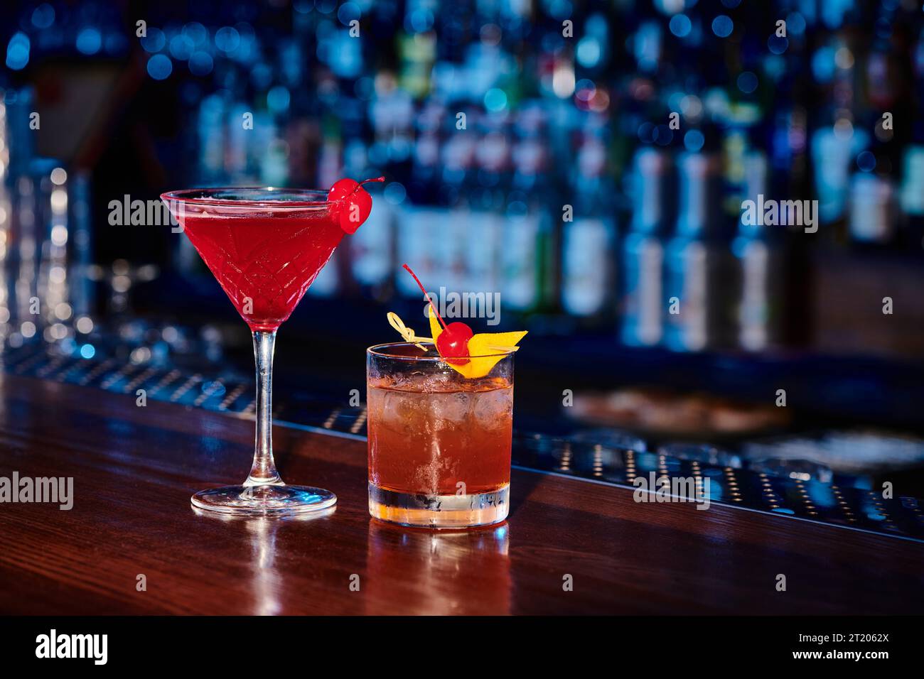 Exotische, raffinierte Cocktails, dekoriert mit Kirschen und Bar im Hintergrund, Konzept Stockfoto
