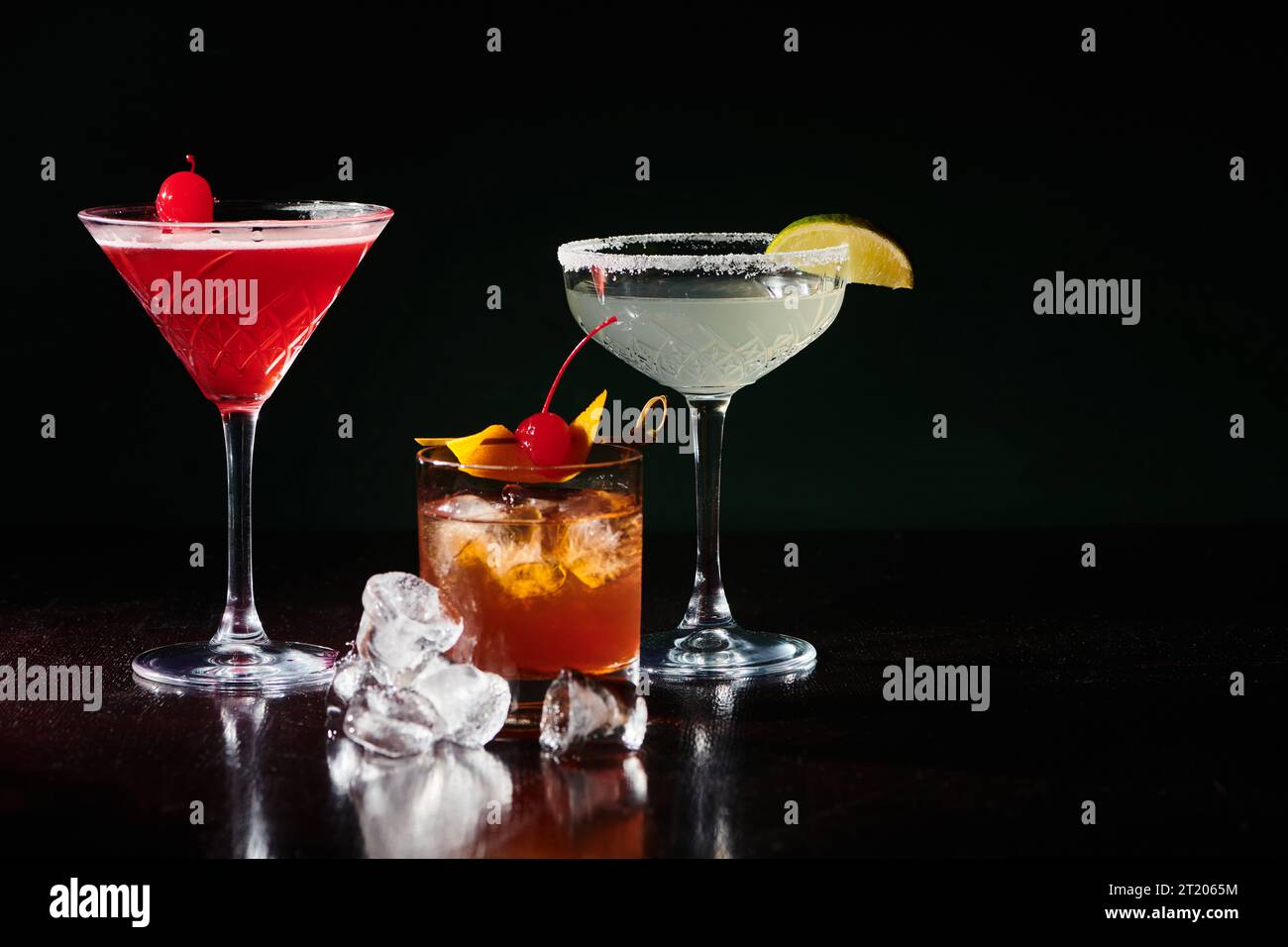 Raffinierte erfrischende Cocktails mit Garnituren auf schwarzem Hintergrund, Konzept Stockfoto
