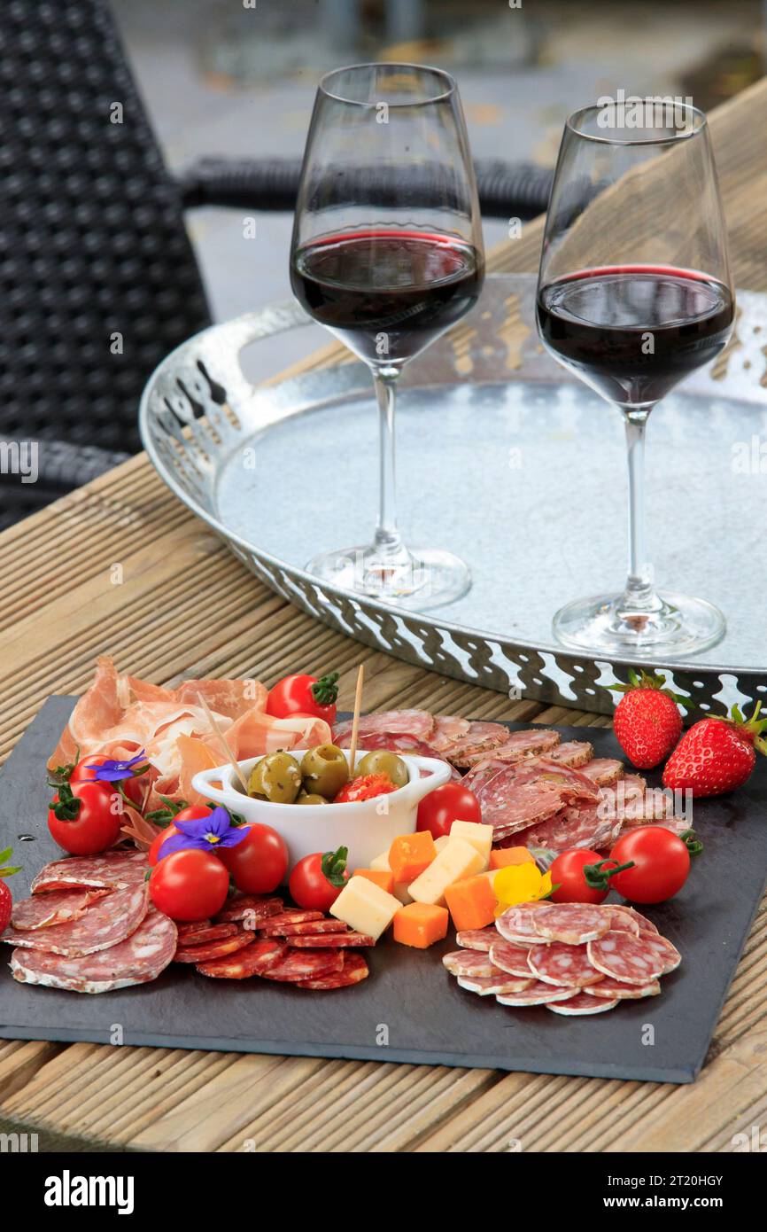Fleischgerichte auf einem Schiefer mit zwei Gläsern Wein Stockfoto