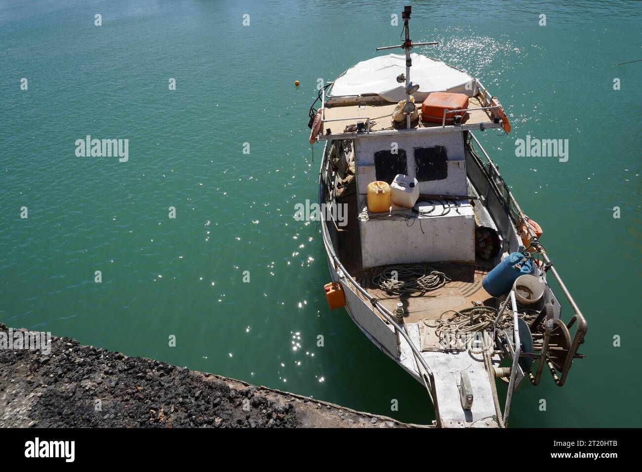 Altes Fischerboot, das am hinteren Teil im Hafen von Heraklion entlang einer Betonmauer verankert ist. Stockfoto