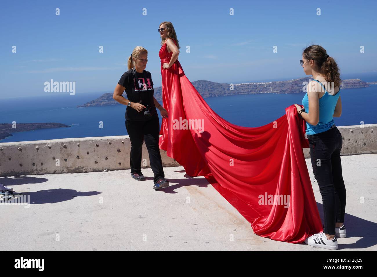 Ein Assistent hält den Zug des Models in einem roten Kleid. Stockfoto