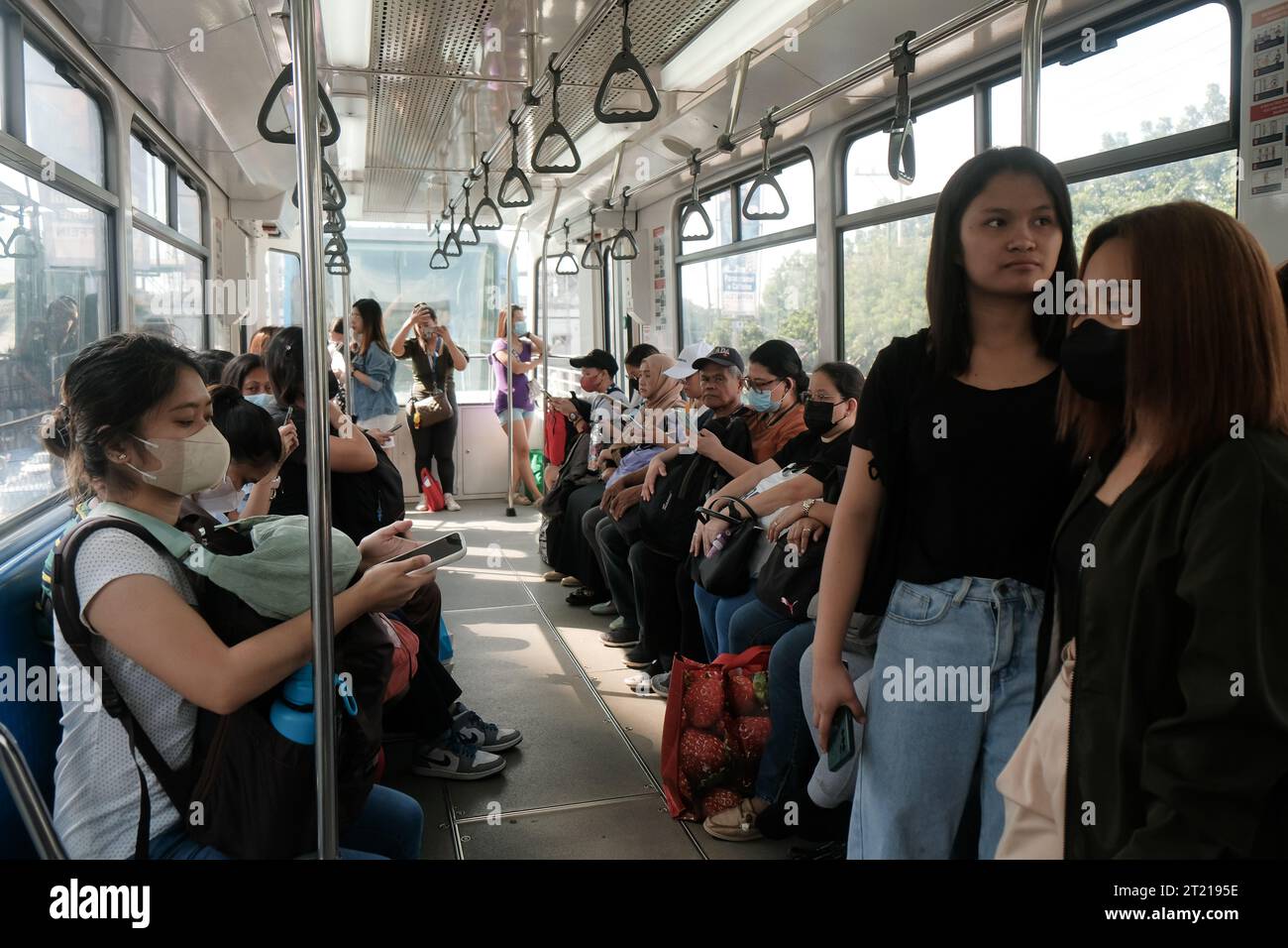 Philippinische Pendler in einer Kabine in einem fahrenden LRT-Zug der Linie 1. Im Apartment mit Straßenbahn Transit 1. Öffentliche Verkehrsmittel in Manila, Philippinen. Stockfoto