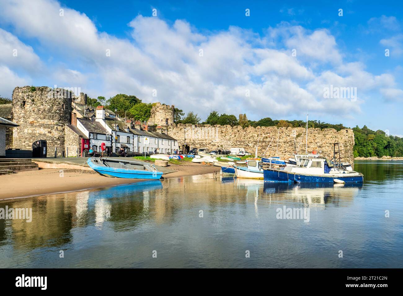 29. September 2023: Conwy, Nordwales - Boote, die entlang der Flussmündung des River Conwy befestigt sind, und Landhäuser, die an den Stadtmauern des 13. Jahrhunderts gebaut wurden, auf einem... Stockfoto