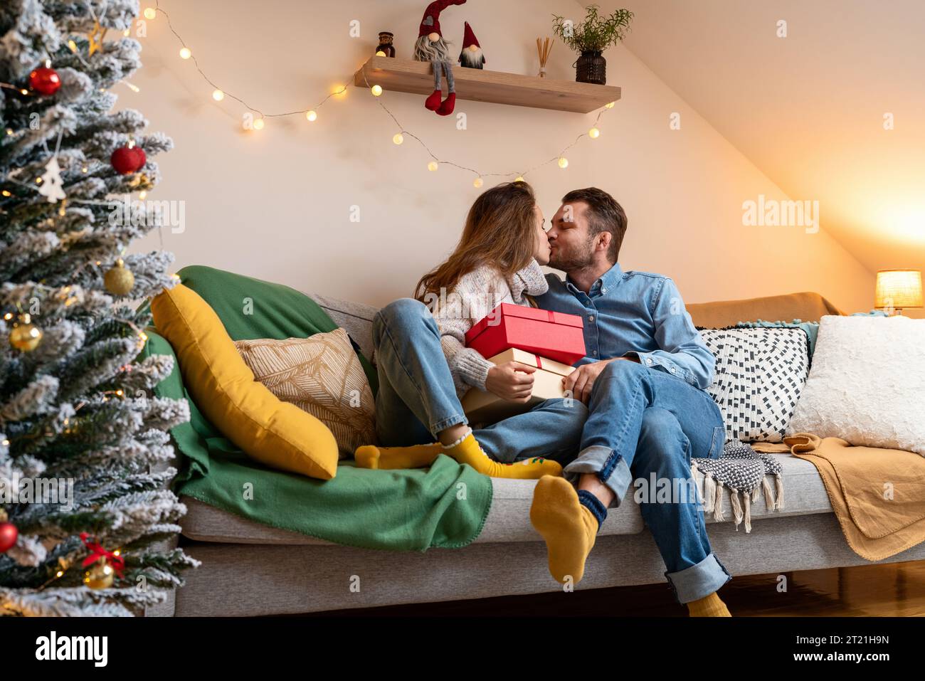 Junge verheiratete Paare geben sich Weihnachtsgeschenke und küssen sich. Weihnachtsfeiertage. Stockfoto