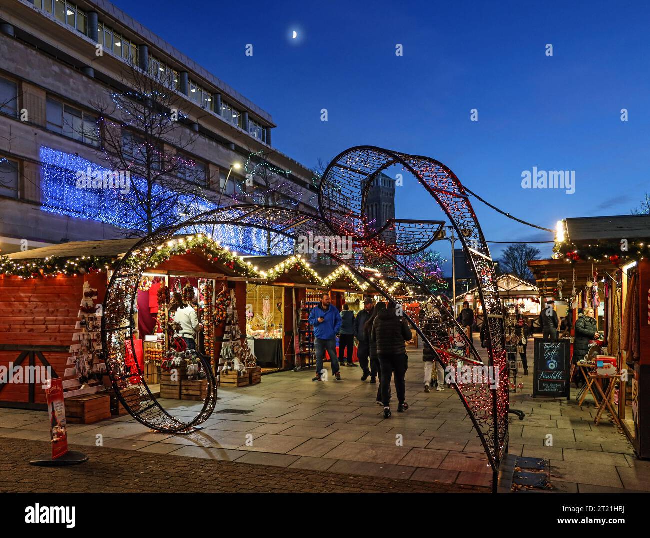 Weihnachtslichter sorgen nach Sonnenuntergang im Jahr 2021 für Wärme an den kleinen Holzständen auf dem Weihnachtsmarkt in Plymouth Stockfoto