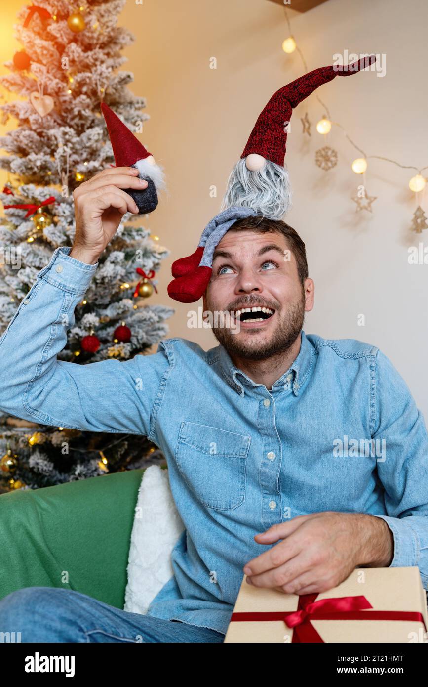 Weihnachtskindlichkeit. Infantil. Erwachsener Mann, der mit Kinderspielzeug spielt, Weihnachtszwerge. Stockfoto