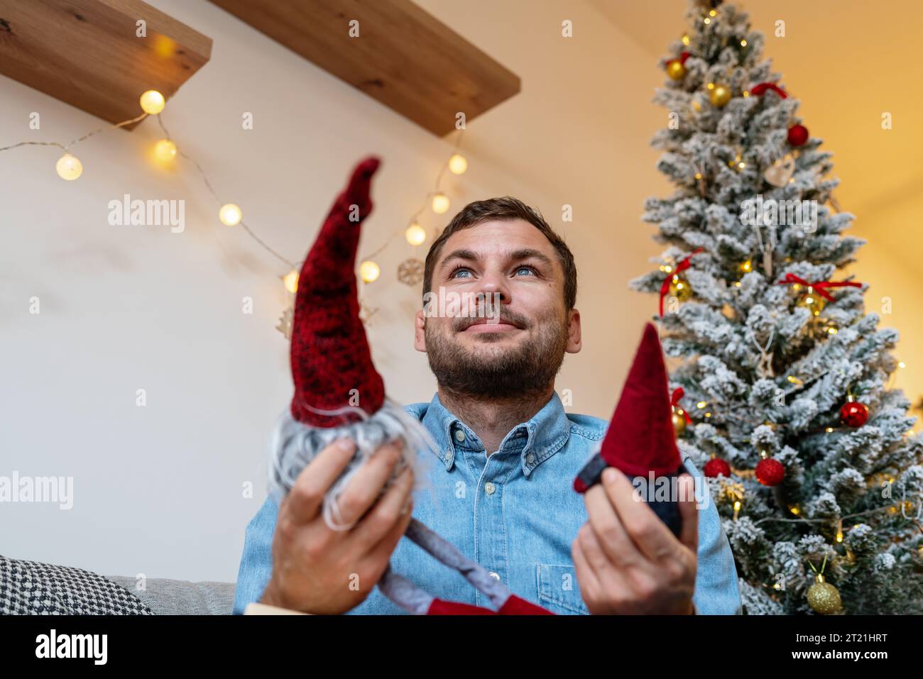 Erwachsener Mann, der Weihnachtsspielzeuggnome in der Hand hält und sich an seine Kindheit erinnert. Stockfoto