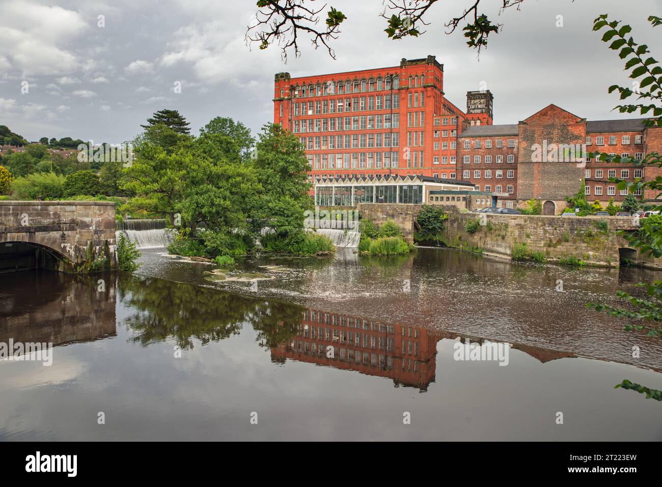 Strutts East Mill (Mitte) und North Mill (rechts) mit dem Hufeisenwehr am Fluss Derwent, Belper, Derbyshire, England Stockfoto
