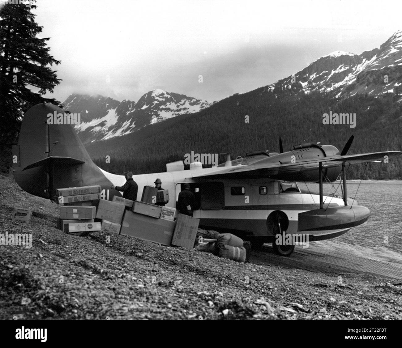 Ein Flugzeug von Grumman Goose entlädt Vorräte in Olson Bay, Alaska. Das Amphibienflugzeug wird an der Küste gezeigt, das für Transport und logistische Unterstützung in abgelegenen Gebieten genutzt wird. Stockfoto