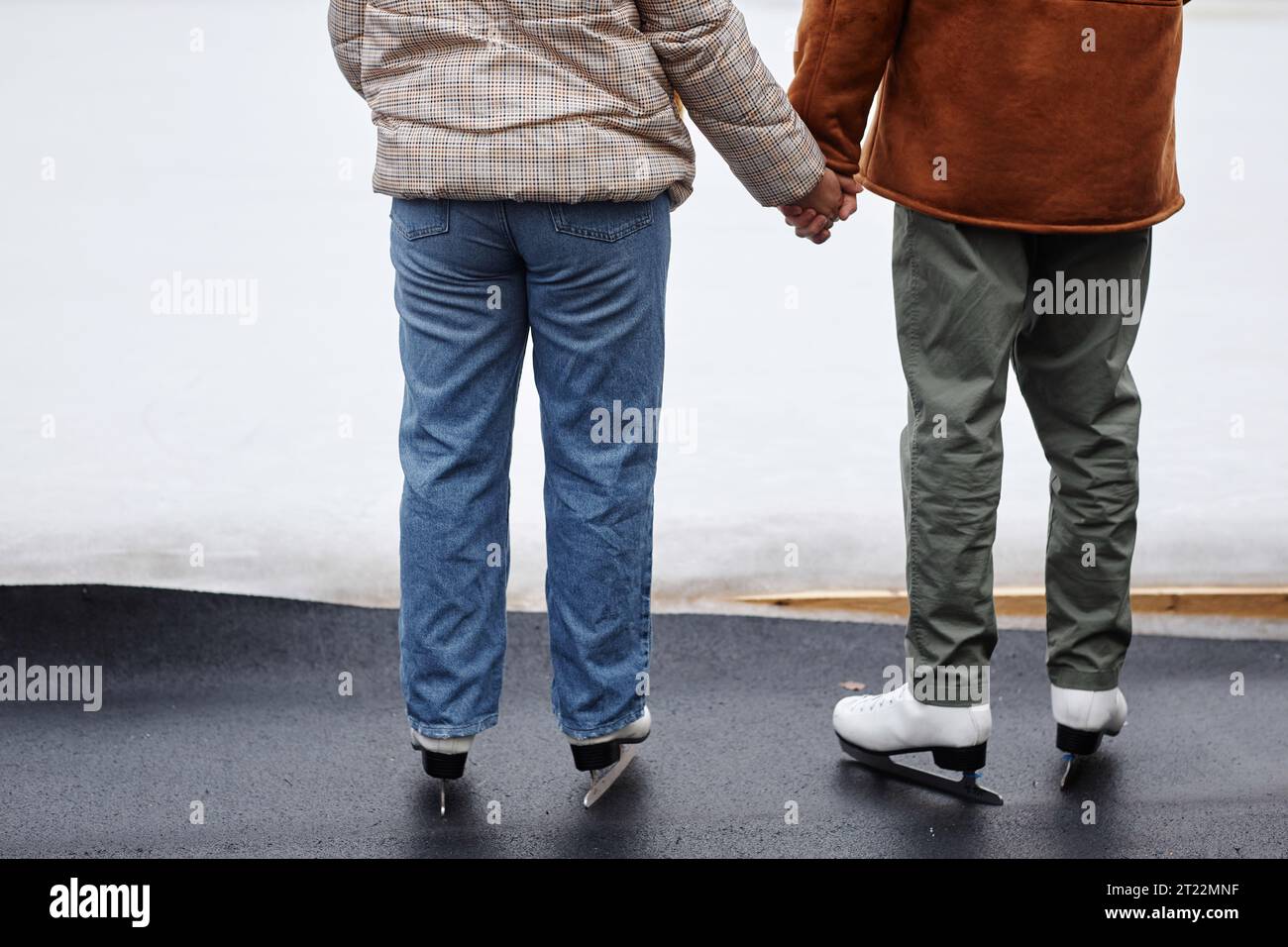 Rückansicht eines nicht erkennbaren Paares, das Hände in der Eislaufbahn hält, Kopierraum Stockfoto