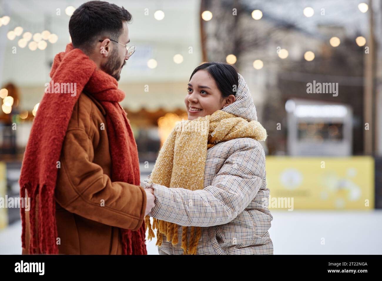 Seitliches Porträt eines jungen Paares im Freien im Winter, das sich an der Eislaufbahn und im Kopierraum erfreute Stockfoto