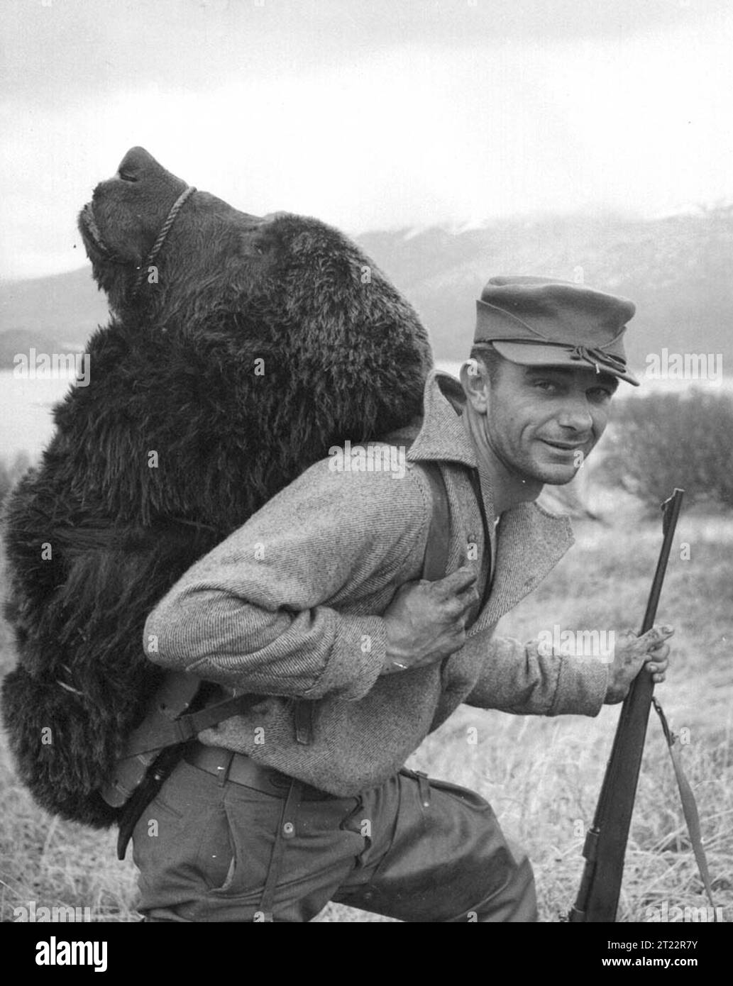 Ein Jäger im Kodiak National Wildlife Refuge trägt einen großen Bärenkopf als Teil einer erfolgreichen Bärenjagd. Die Bärenjagd ist eine wichtige Freizeitaktivität innerhalb des Schutzgebiets, die die Tierbewirtschaftung und die Kontrolle der Bevölkerung unterstützt. Stockfoto