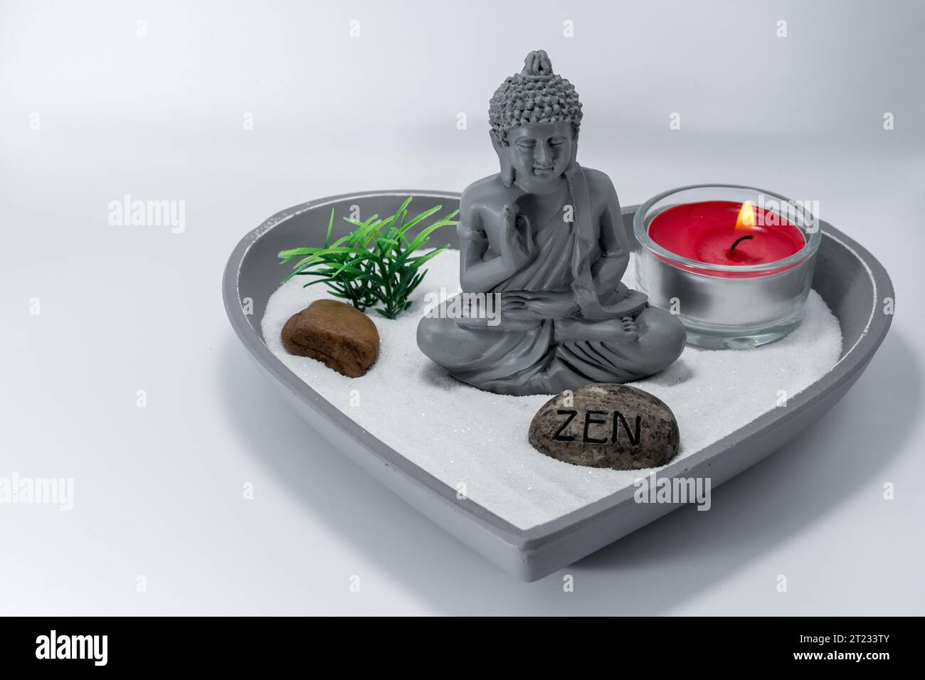 Zen-Garten. Spirituelle Buddha-Dekoration für eine ruhige, ruhige und konzentrierte Atmosphäre. Kerze, die Aromen in einer entspannenden Oase freisetzt. Stockfoto