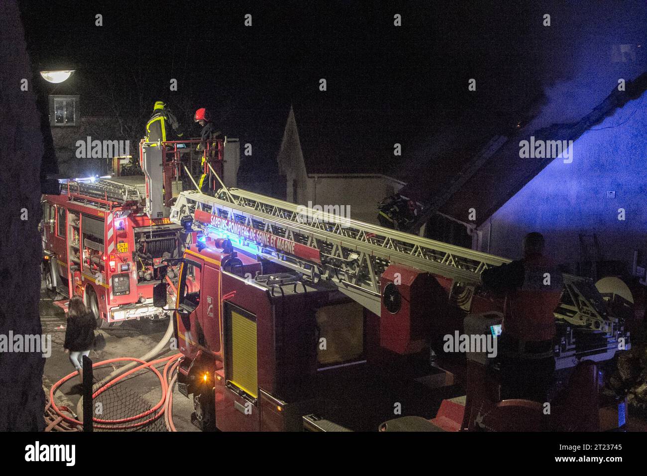 Feuerwehrleute treffen nachts in einem Dorf in Frankreich am Ort eines Hausbrandes ein und bereiten sich darauf vor, die Leiter zu verlängern. Stockfoto