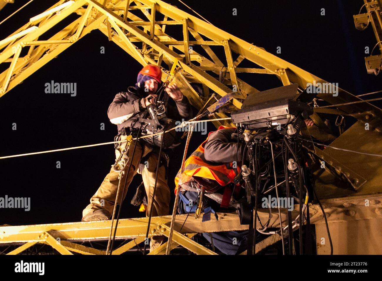 Elektriker, die die Beleuchtung mitten in der Nacht in der Nähe des Eiffelturms wechseln, im Winter in Paris, Frankreich. Stockfoto