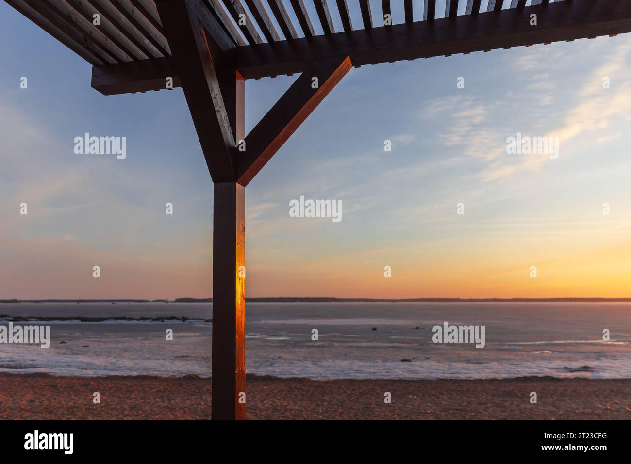 Am Abend ist ein hölzerner Sonnenschirm an der Küste, im Hintergrund liegt die Winterlandschaft des Strandes Stockfoto