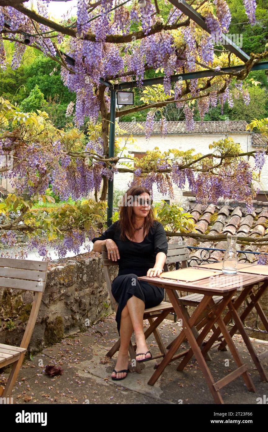 Frau saß an einem Tisch auf der Terrasse eines kleinen Landcafés in Perigord im Südwesten Frankreichs. Stockfoto