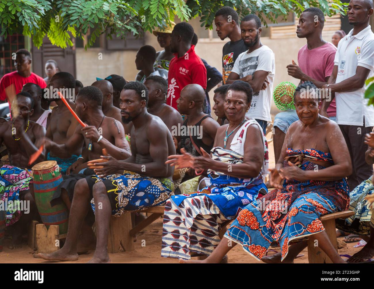 Lome, Togo - 14. Mai 2023. Einheimische Dorfbewohner sitzen auf Bänken und beobachten eine traditionelle Voodoo-Zeremonie in ihrem Dorf. Stockfoto