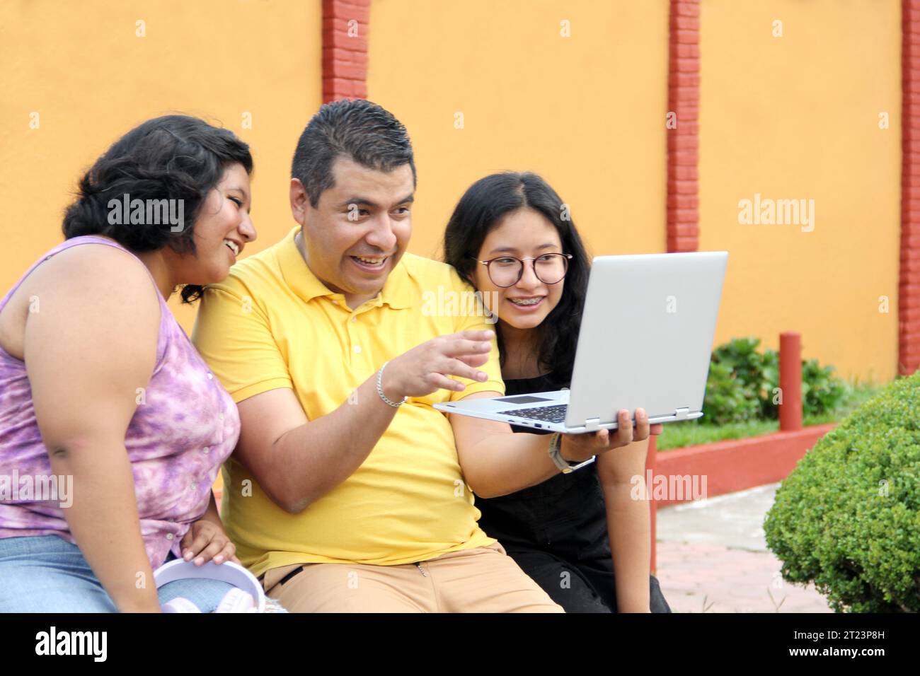 Dunkelhäutige Latino-Papa und -Töchter nutzen ihr Notebook zusammen und verbringen Zeit mit Spielen, Hausaufgaben, Lernen und Videos Stockfoto