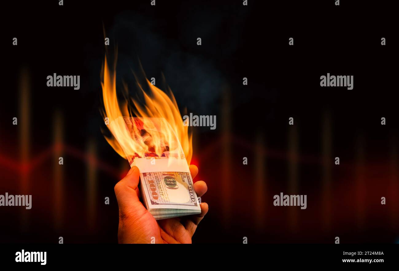 Brennendes Geld in der Hand auf dunklem Hintergrund mit Kopierraum für Text, Dollarscheine mit Feuer in der Hand. Finanz- oder Währungskrisenkonzept Stockfoto