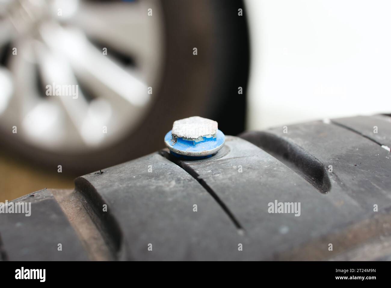 Schließen Sie ein Autoreifen, das mit Metallschrauben am Reifen durchstochen ist, und scharfe Schrauben durchstechen die Seite des Autoreifens. Automobilkonzept Stockfoto