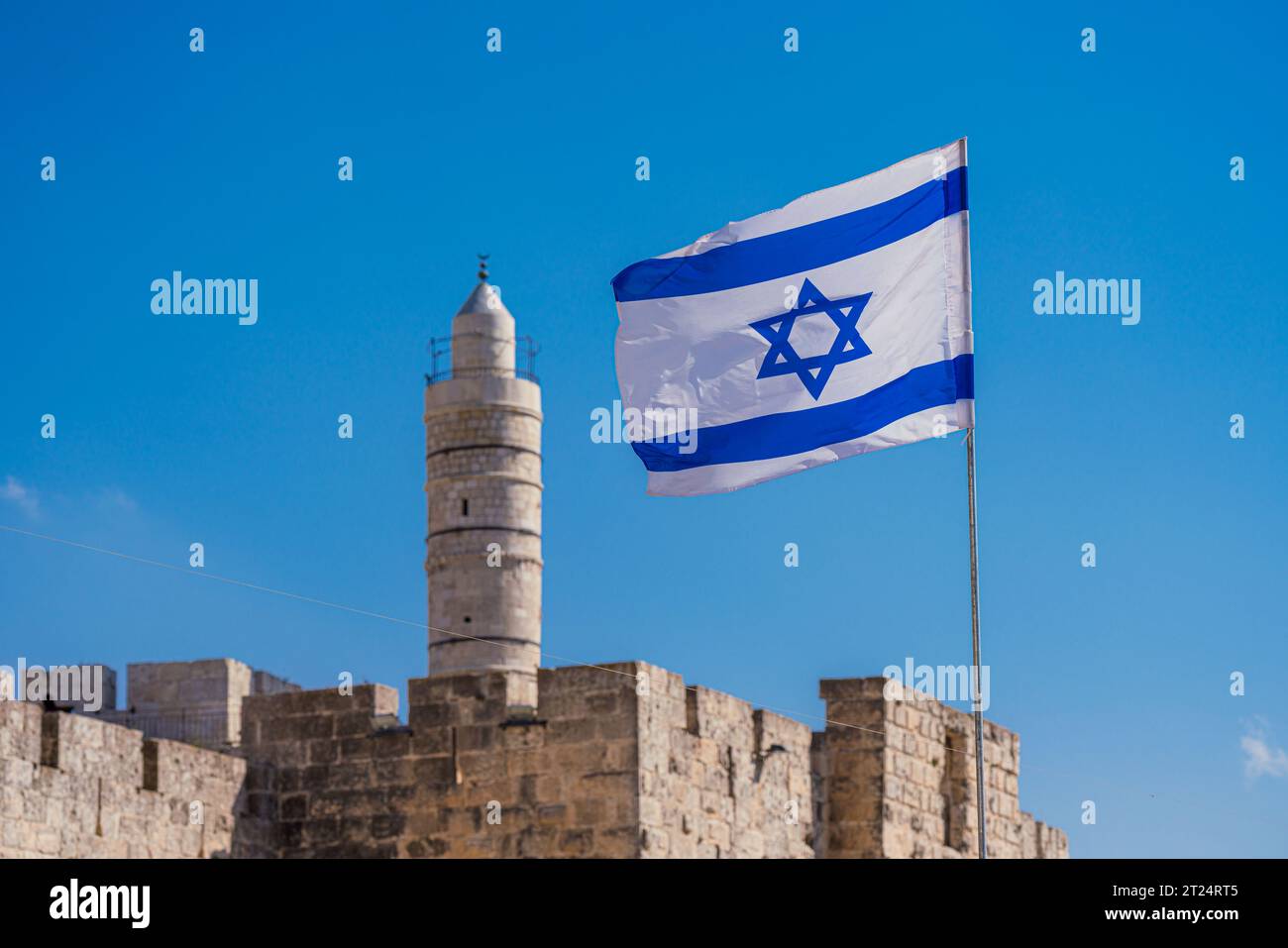 Israels Flagge winkt gegen den blauen Himmel, der Davidsturm im Hintergrund ist verschwommen Stockfoto