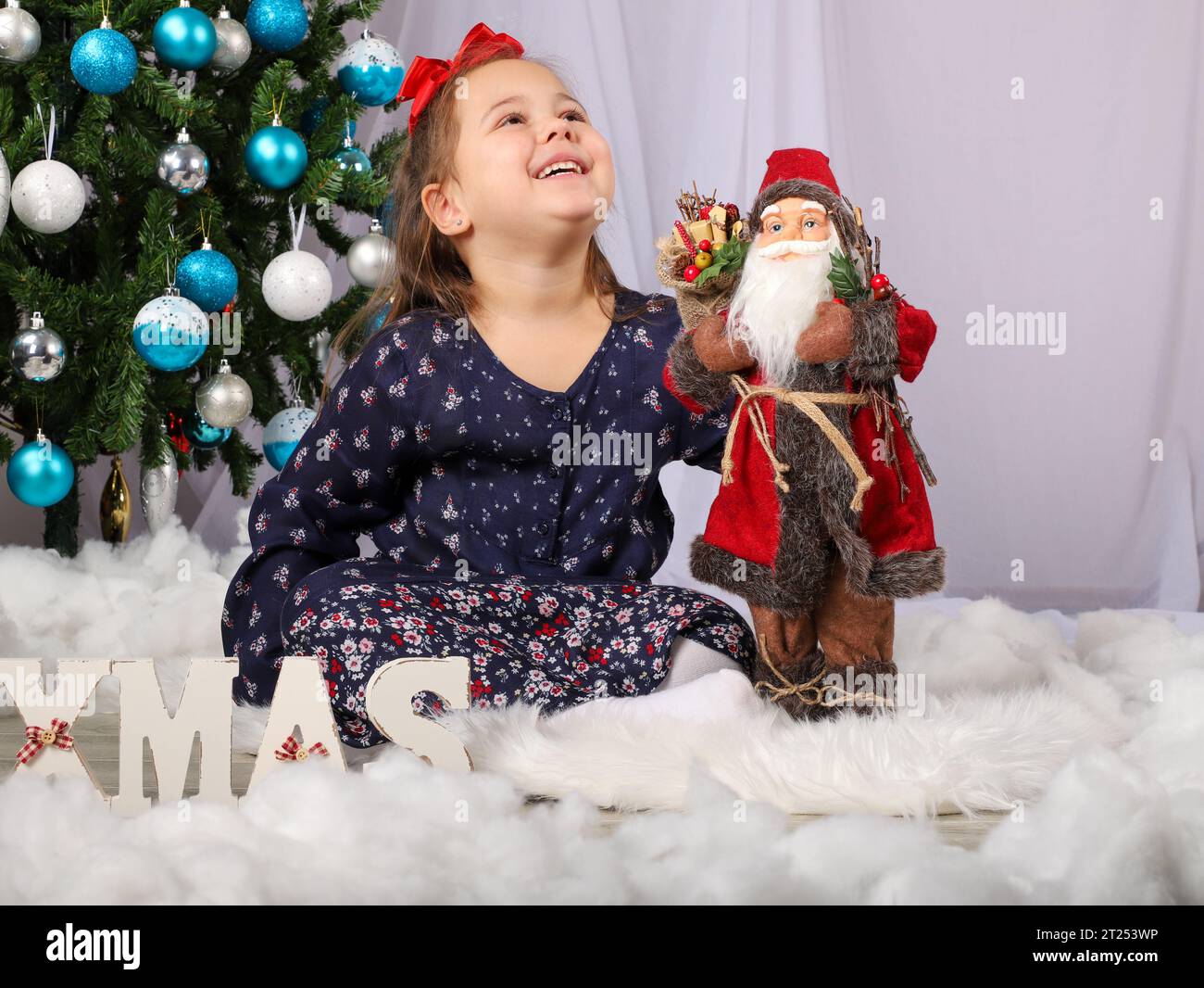 Schönes kleines Mädchen in lila Kleid vor dem weihnachtsbaum Stockfoto