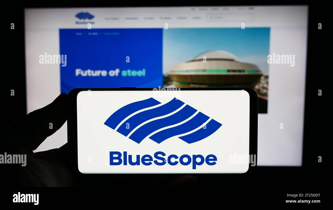 Person mit Smartphone und Logo des australischen Unternehmens BlueScope Steel Limited vor der Website. Schwerpunkt auf dem Display des Telefons. Stockfoto