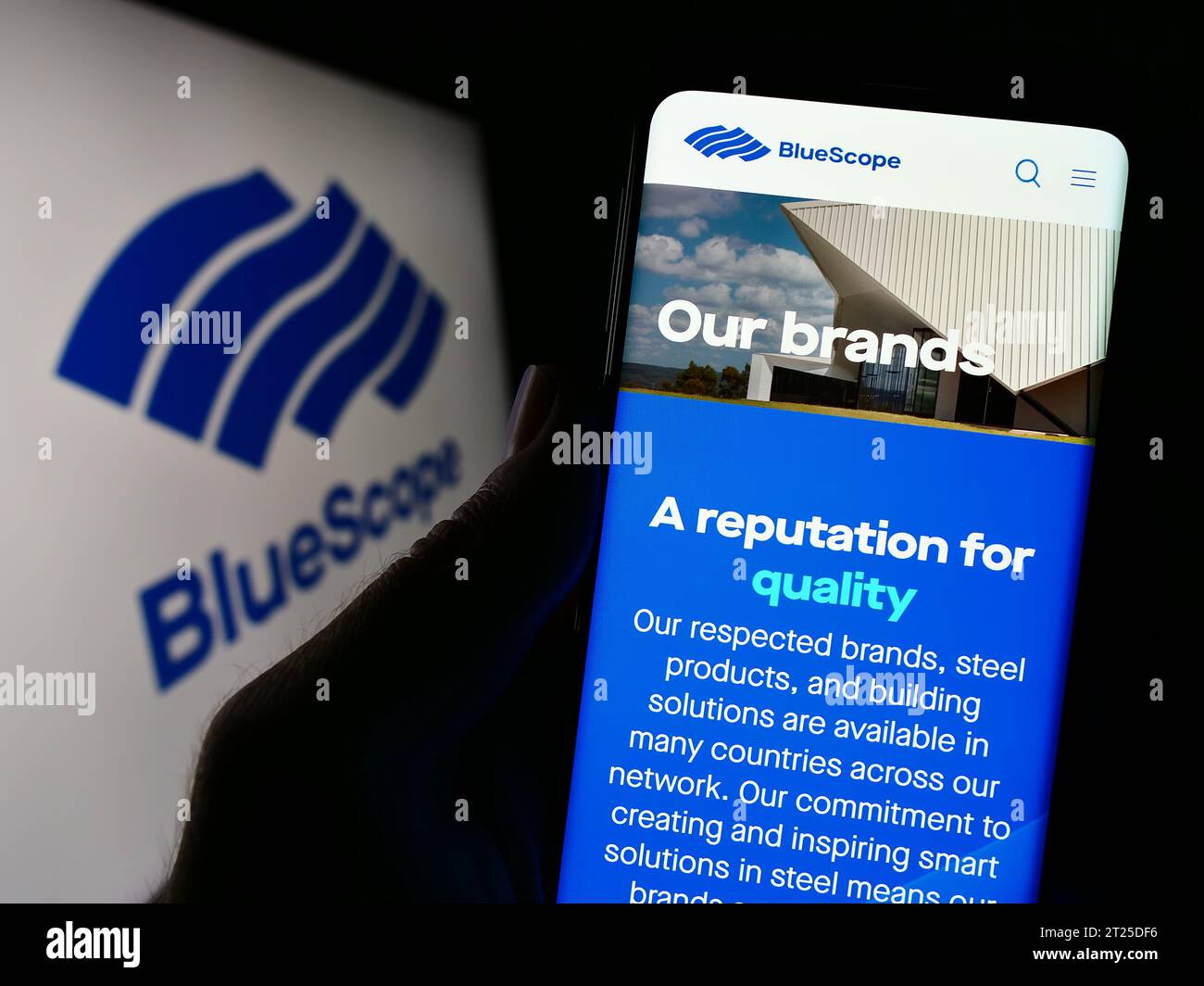 Person, die ein Handy hält, mit Webseite der australischen Firma BlueScope Steel Limited vor dem Logo. Konzentrieren Sie sich auf die Mitte des Telefondisplays. Stockfoto