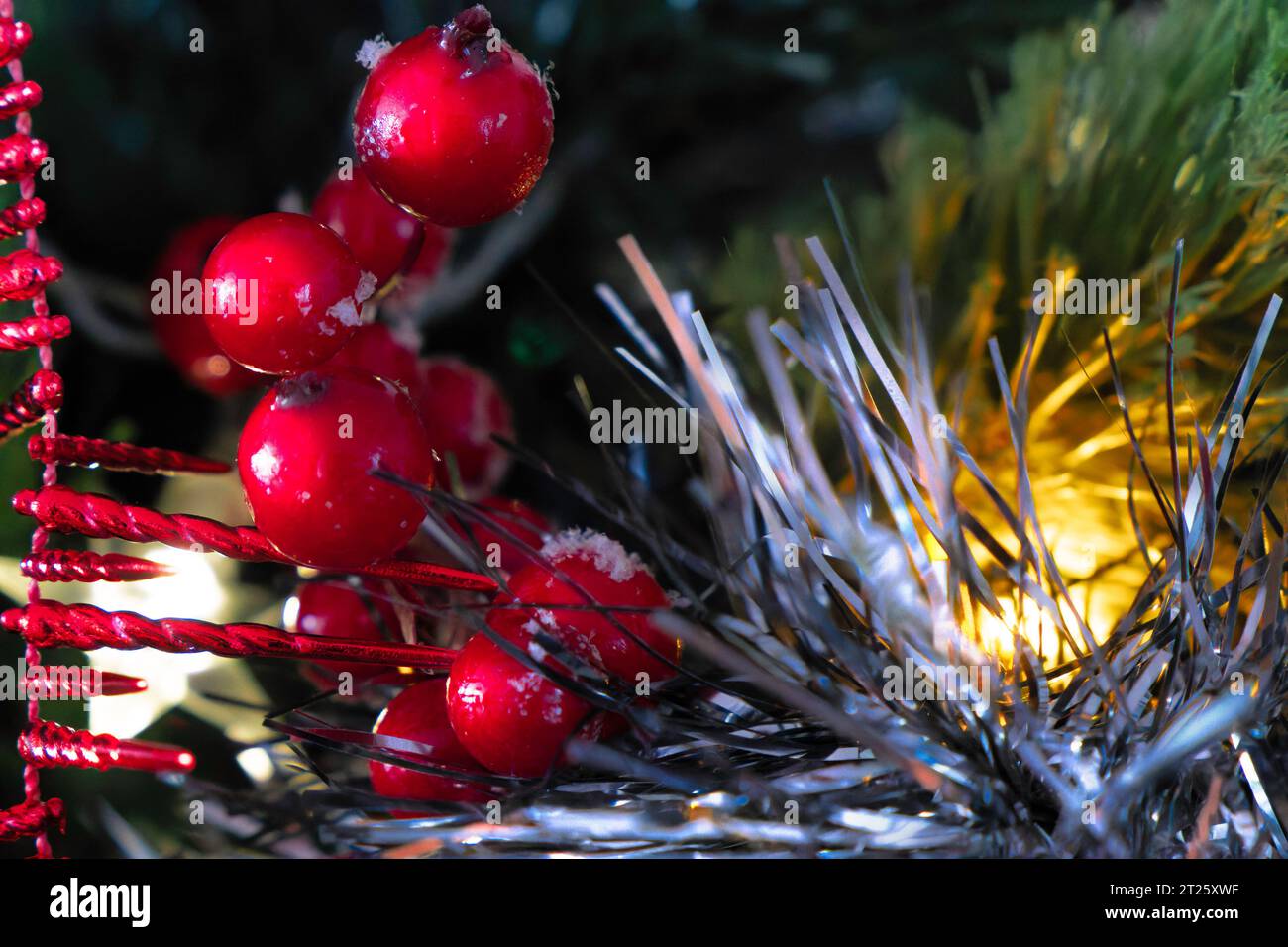 Weihnachtsdekoration auf einem weihnachtsbaum. Lametta, Girlanden und stechpalmenfrüchte. Nahaufnahme. Selektiver Fokus Stockfoto