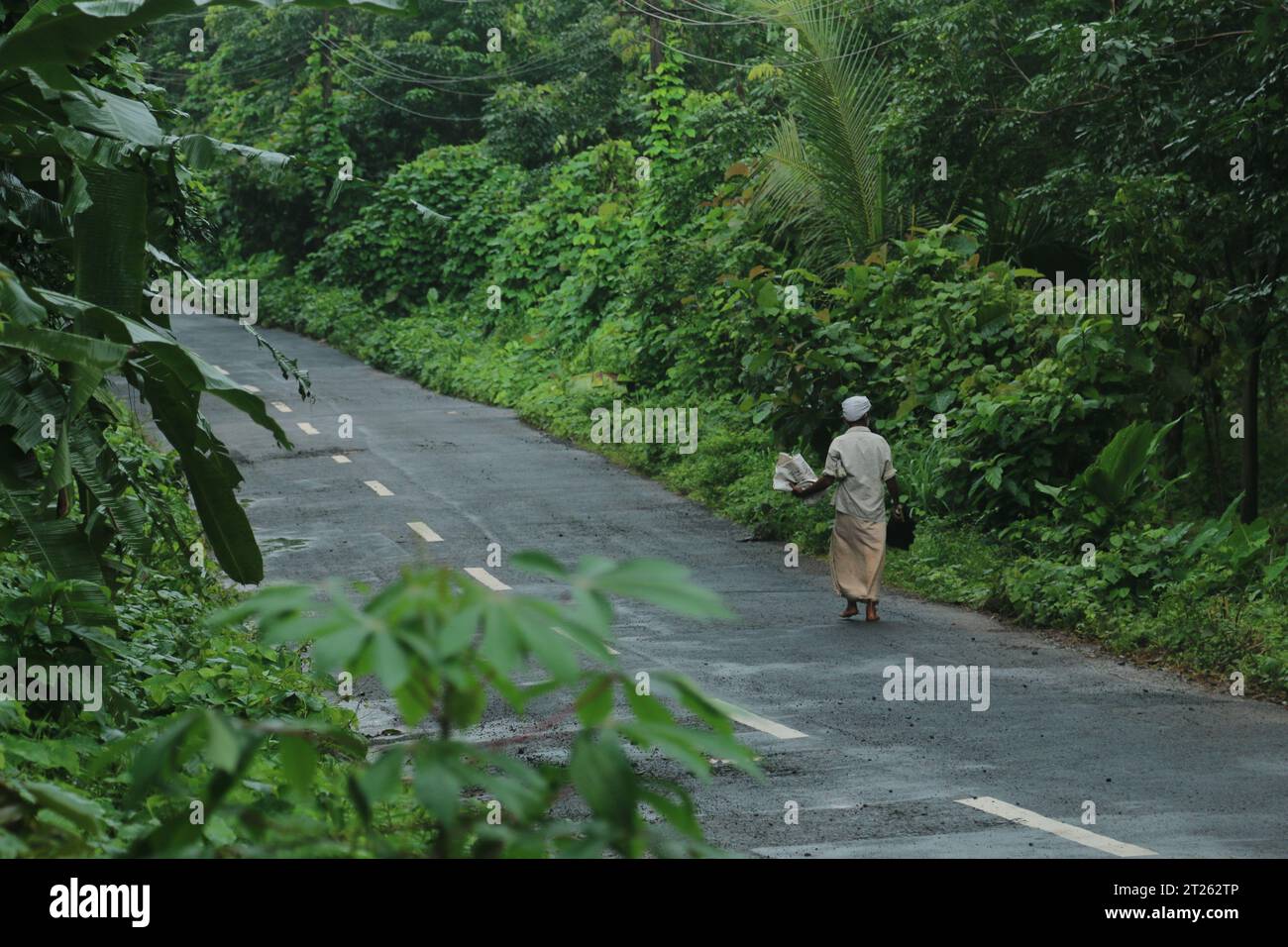 Ein alter Mann, der am frühen Morgen in Kerala unterwegs ist. Stockfoto
