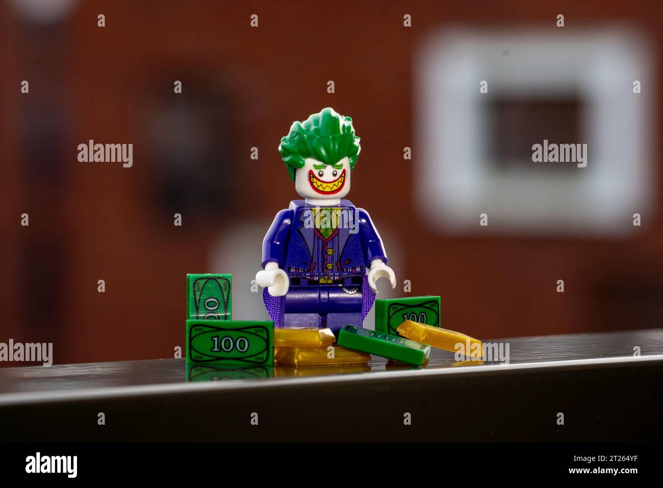 Eine Lego-Minifigur des Jokers, die hinter einem Haufen Geld und Gold steht Stockfoto