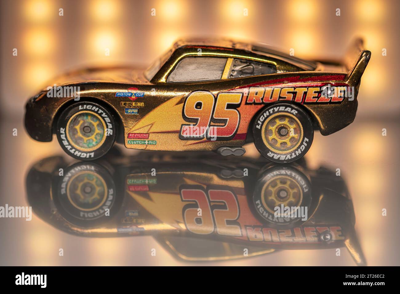 Madrid, Spanien; 09-30-2023: Spielzeugauto namens Lightning McQueen aus der berühmten Pixar Cars-Reihe, goldfarben mit gelben Lichtern und reflektiert auf Th Stockfoto