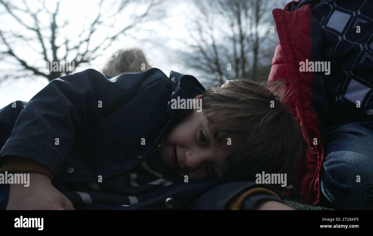 In der Herbstsaison liegt das Gesicht des Kindes im Kreisverkehr auf dem Spielplatz, während das Kind an kalten Tagen eine Jacke trägt und an sonnigen Tagen im Freien spielt Stockfoto