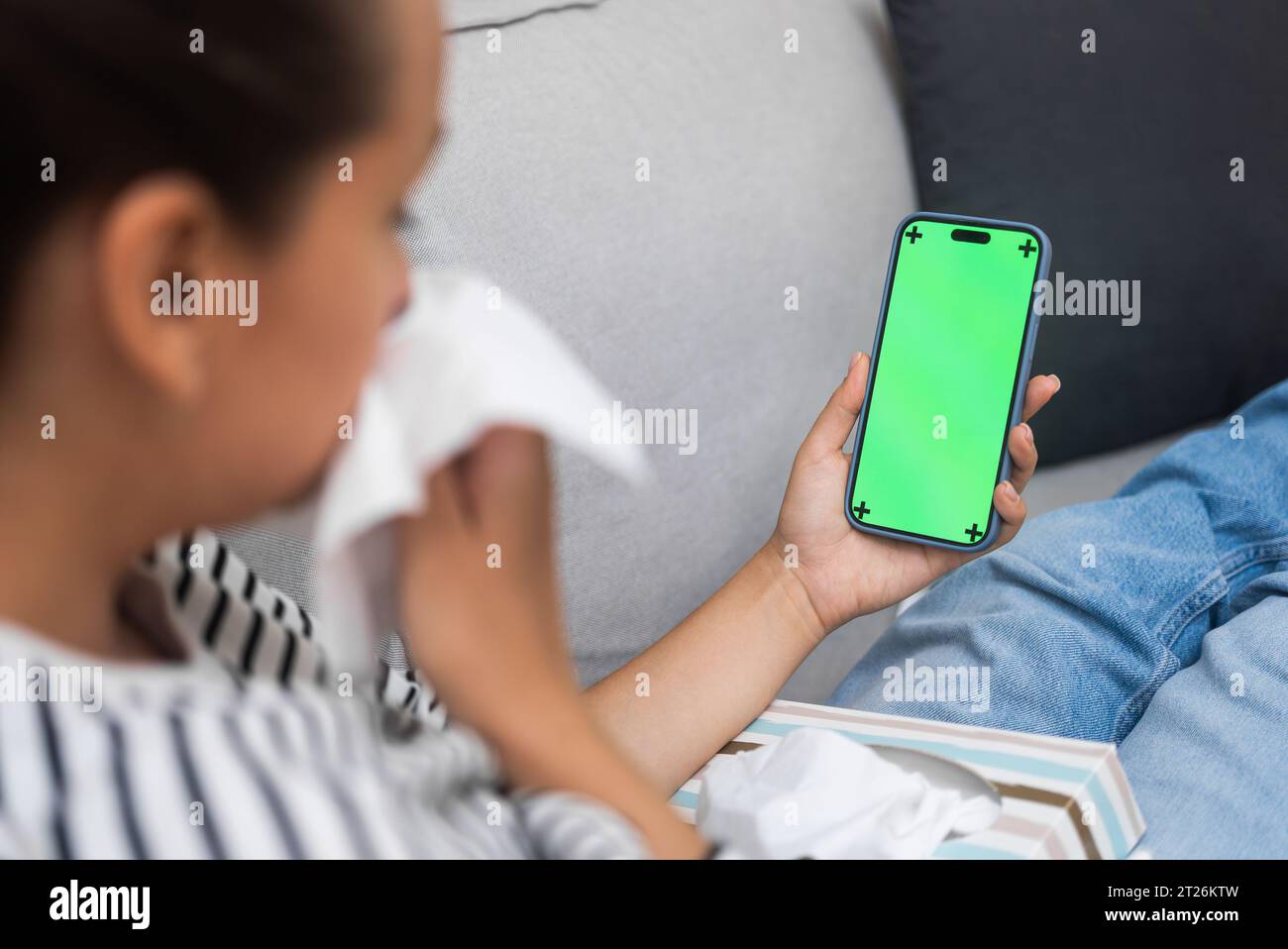 Kranke Frau mit laufender Nase kommuniziert mit dem Arzt über ein Mobiltelefon mit Chromakey-Bildschirm Stockfoto